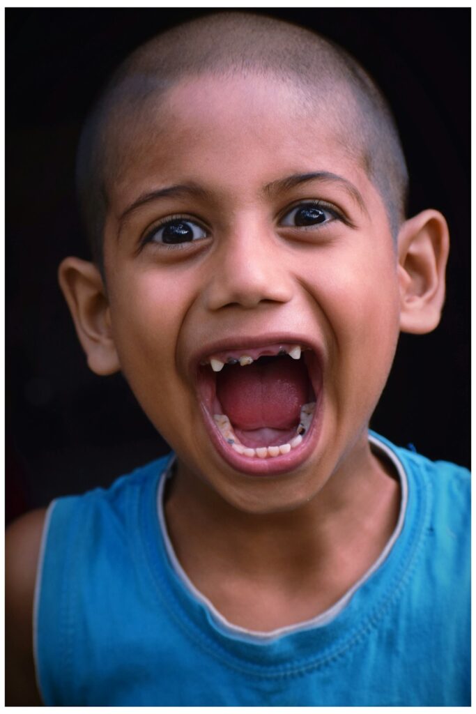 A young child holding a chipped tooth fragment while a parent gently inspects their mouth in a home setting.