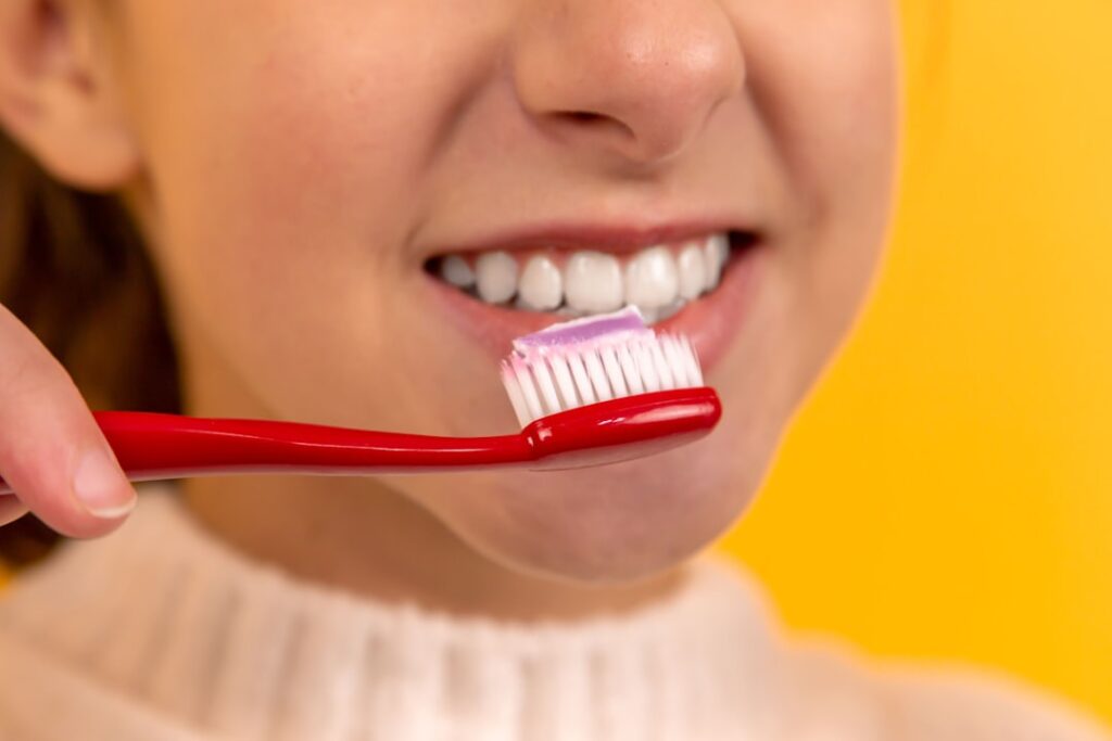A close-up of a person brushing their teeth in a brightly lit bathroom.