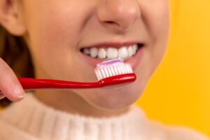 A close-up of a person brushing their teeth in a brightly lit bathroom.