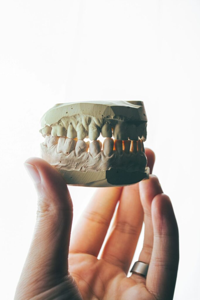 Adult examining a brighter smile beside a bathroom mirror with a whitening tray and toothbrush nearby.